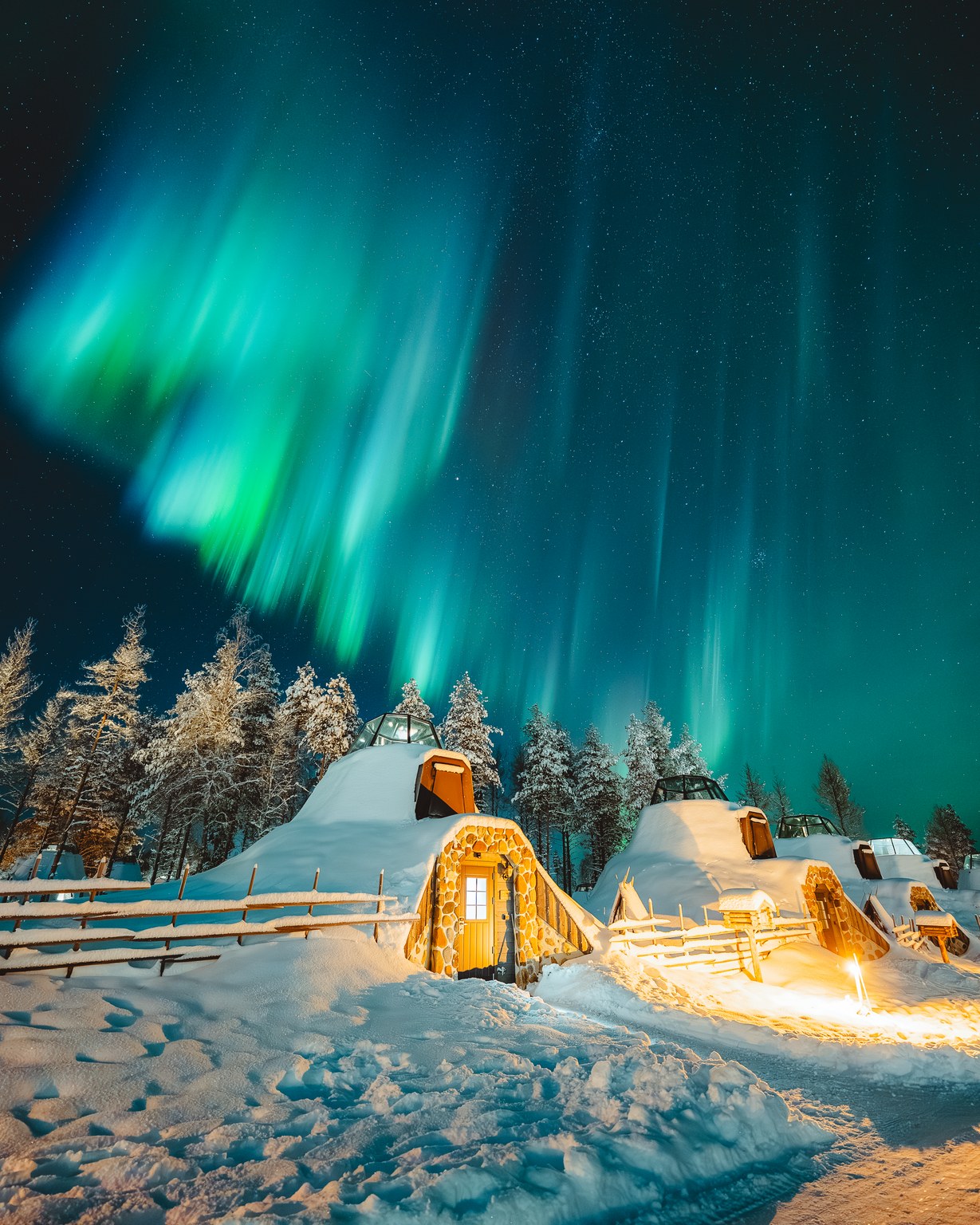 Glass igloos under bright Northern Lights