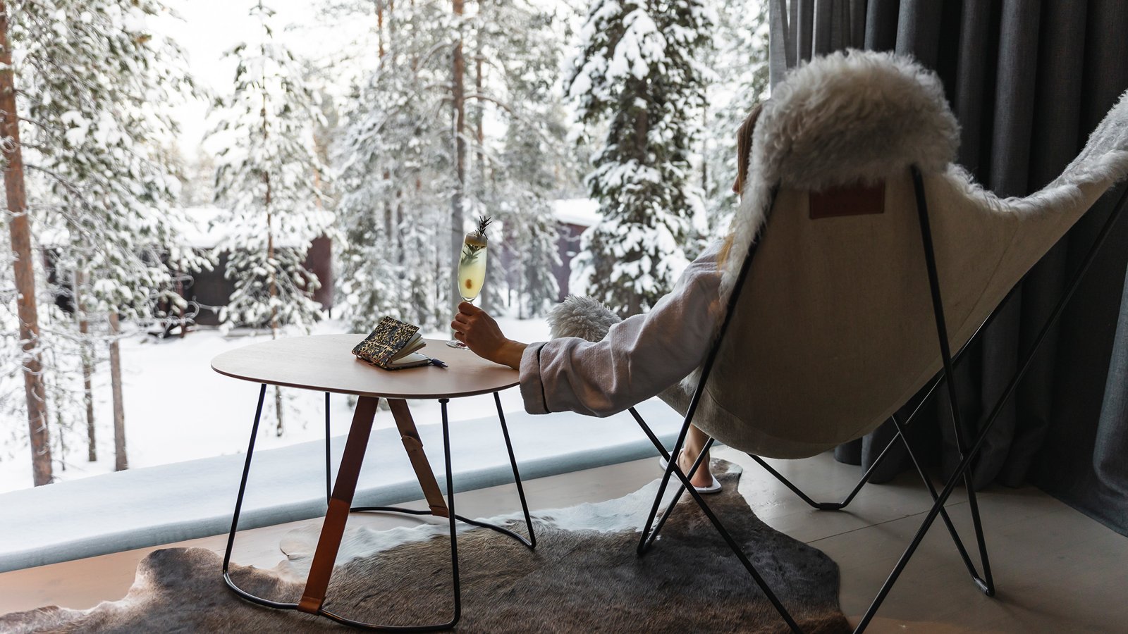 Guest relaxing by a window overlooking the winter forest