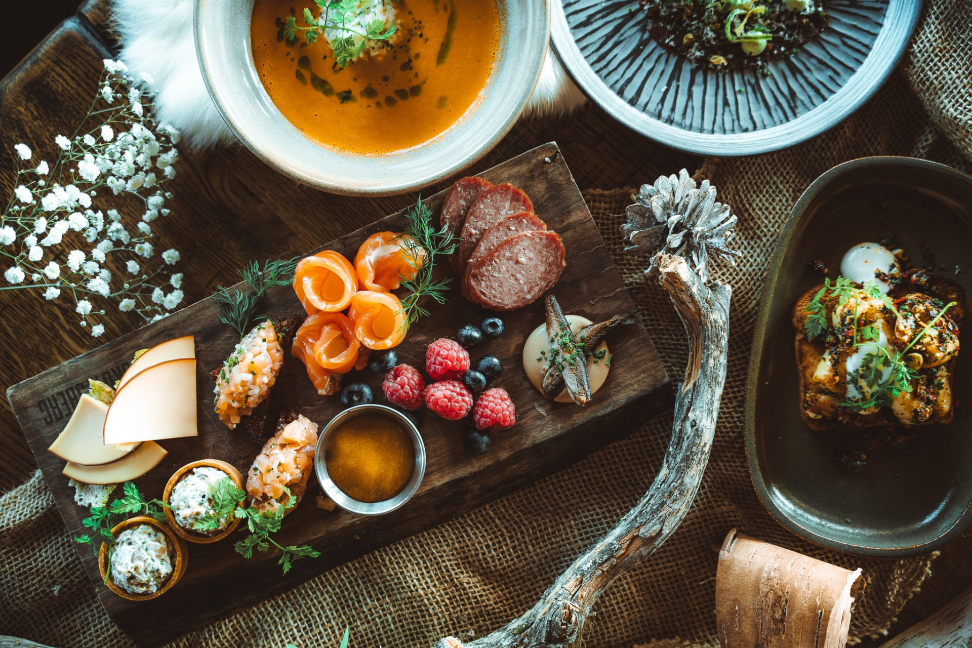 Table of modern Lappish dishes with smoked fish, berries and soup