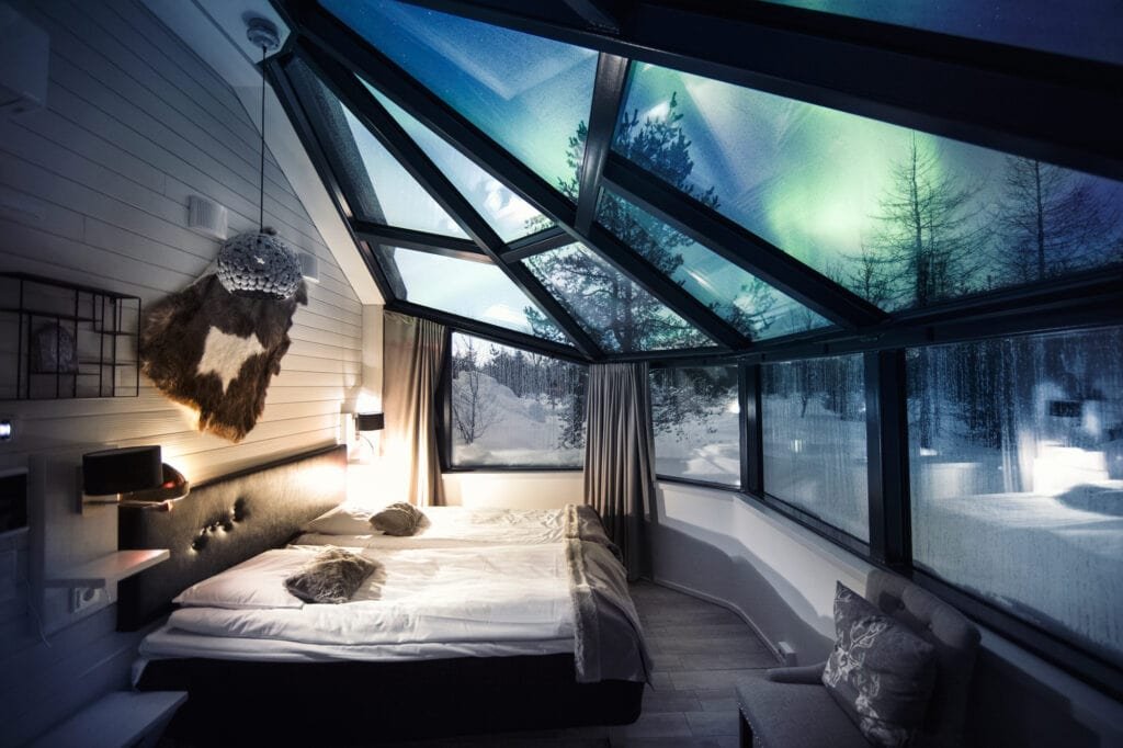 Glass igloo bedroom with aurora visible through the roof