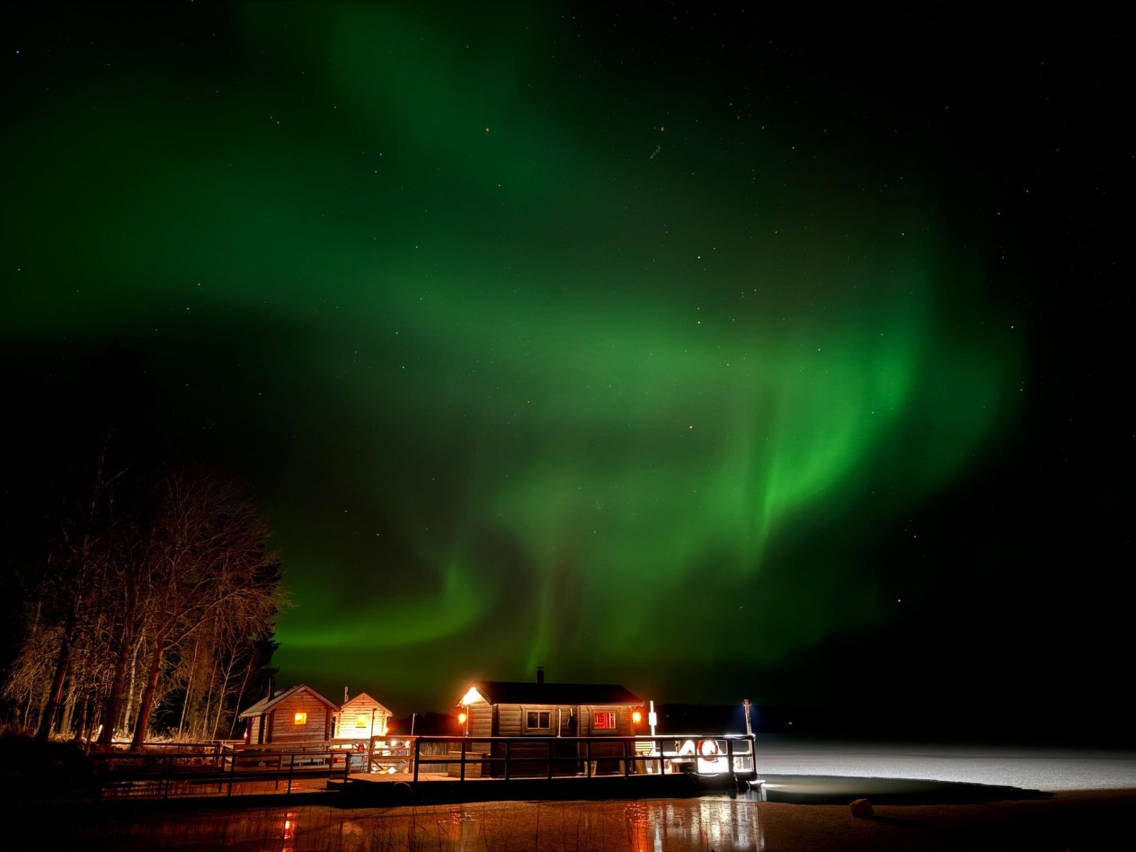 Aurora over a lakeside sauna at night